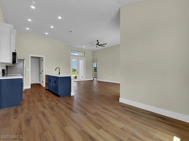 unfurnished living room with ceiling fan, hardwood / wood-style floors, french doors, and sink