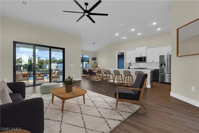 living room featuring wood-type flooring, ceiling fan, lofted ceiling, and sink