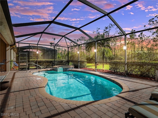 pool at dusk featuring a lanai, a patio area, and an in ground hot tub