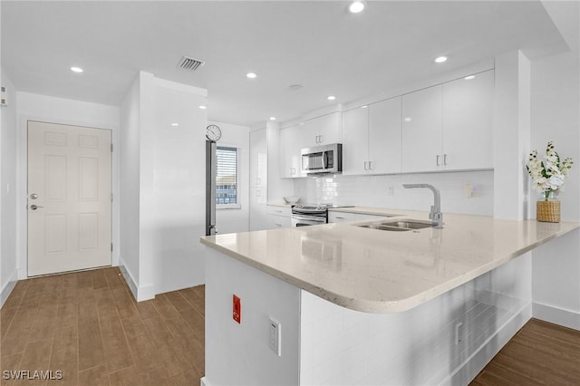 kitchen featuring white cabinets, appliances with stainless steel finishes, wood-type flooring, sink, and kitchen peninsula