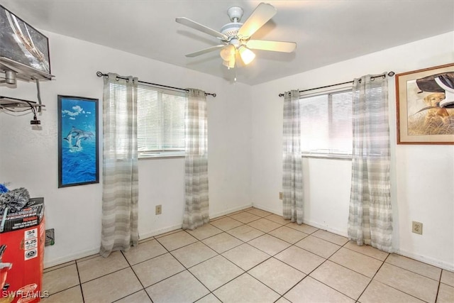 empty room featuring ceiling fan, baseboards, and light tile patterned floors