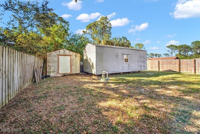 view of yard with a fenced backyard, an outdoor structure, and a storage unit