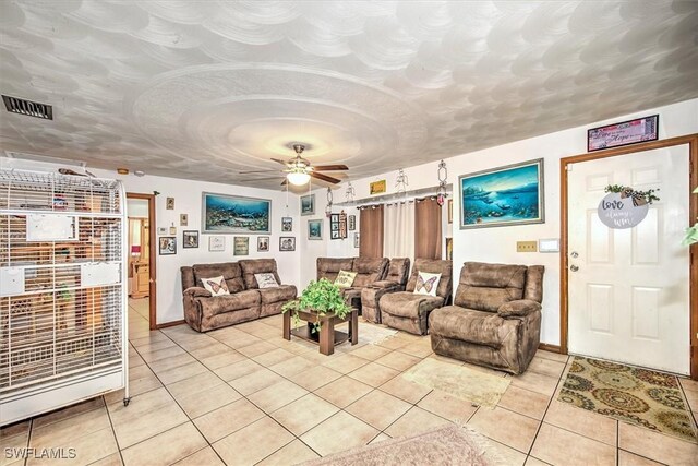 living room featuring light tile patterned floors, a ceiling fan, visible vents, and a textured ceiling