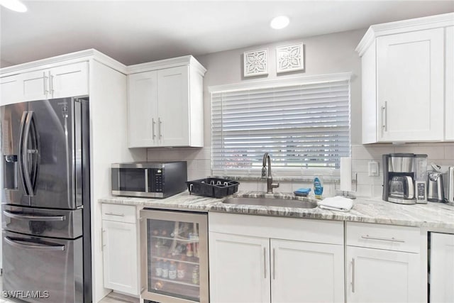 kitchen featuring wine cooler, sink, white cabinets, and stainless steel appliances