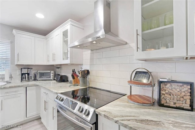 kitchen featuring white cabinetry, wall chimney exhaust hood, light stone counters, and stainless steel electric range