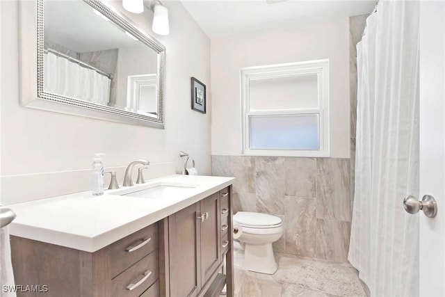 bathroom with vanity, toilet, and tile walls