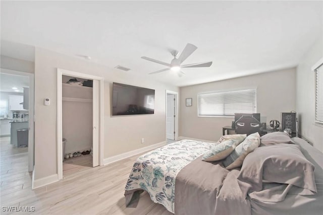 bedroom featuring ceiling fan, light hardwood / wood-style floors, connected bathroom, and a closet