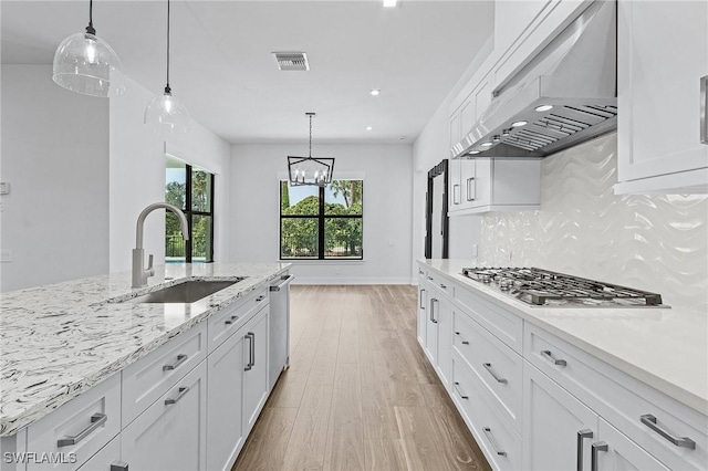 kitchen featuring white cabinets, decorative backsplash, wall chimney exhaust hood, and sink