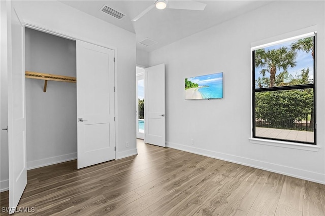 unfurnished bedroom featuring a closet, baseboards, a ceiling fan, visible vents, and wood finished floors