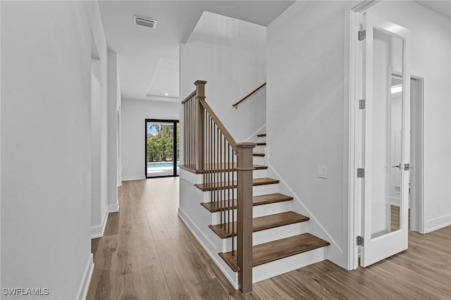 stairs featuring visible vents, baseboards, and wood finished floors