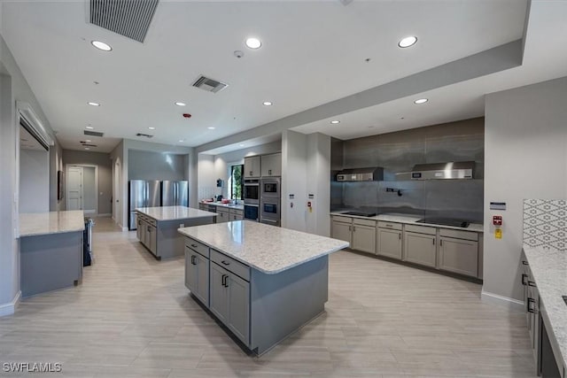 kitchen with light stone countertops, a center island, gray cabinets, and stainless steel appliances