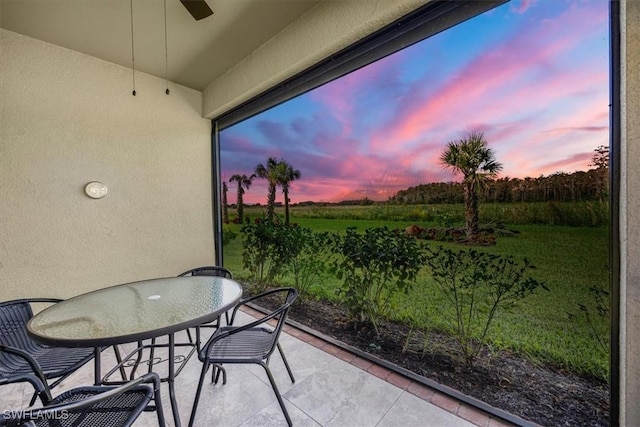 balcony at dusk featuring ceiling fan and a patio