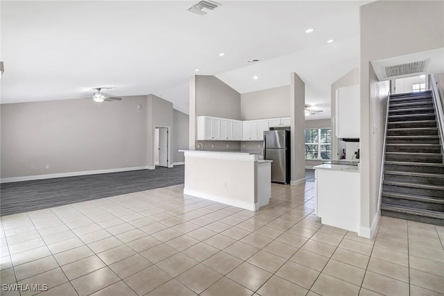 kitchen featuring white cabinets, light tile patterned floors, stainless steel refrigerator, and ceiling fan