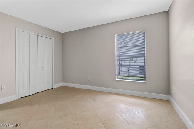 unfurnished bedroom with light tile patterned floors and a closet