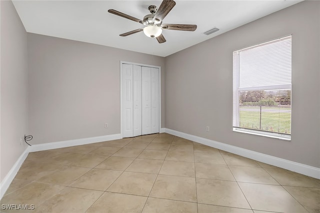 unfurnished bedroom featuring ceiling fan, a closet, and light tile patterned floors