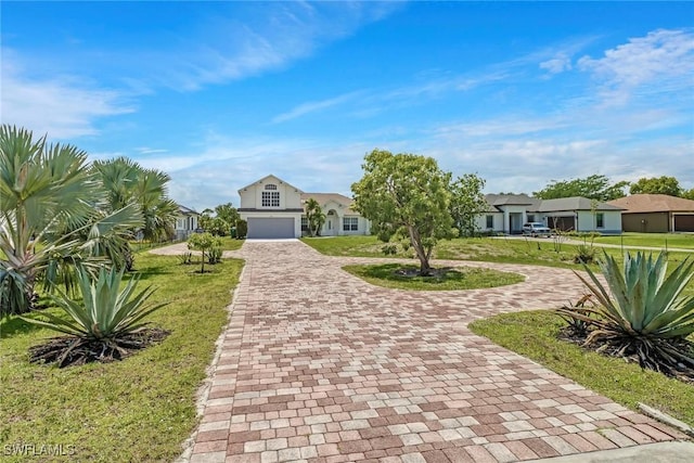 view of front facade featuring an attached garage, decorative driveway, a front yard, and a residential view