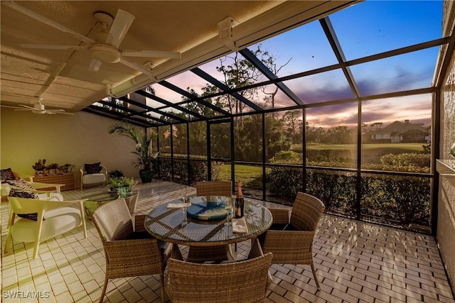 patio terrace at dusk featuring ceiling fan and glass enclosure