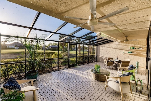 view of patio / terrace featuring ceiling fan and glass enclosure