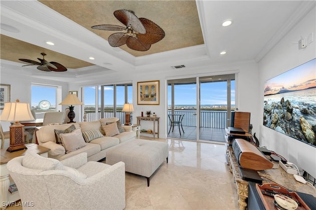 living room featuring a tray ceiling, ceiling fan, ornamental molding, and a water view