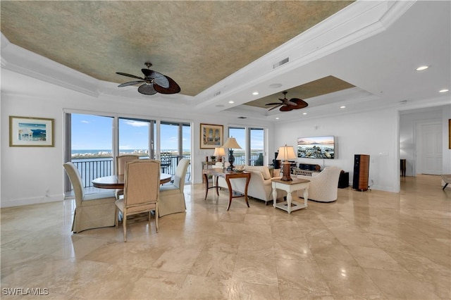 dining area featuring a water view, ceiling fan, ornamental molding, and a raised ceiling