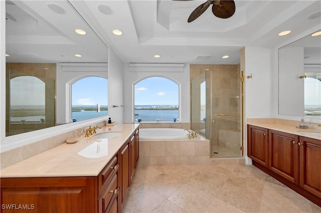 bathroom with vanity, a raised ceiling, a water view, ceiling fan, and independent shower and bath