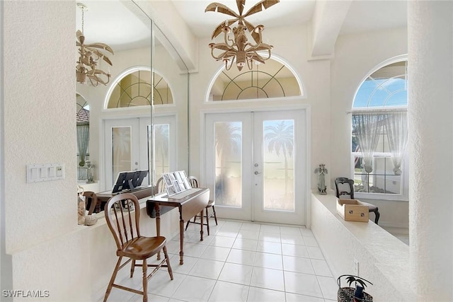 entrance foyer with a towering ceiling, french doors, and light tile patterned floors