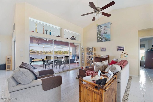 living room with high vaulted ceiling, a water view, light hardwood / wood-style flooring, and ceiling fan