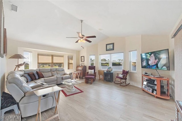 living room featuring lofted ceiling, light wood-type flooring, ceiling fan, and a healthy amount of sunlight