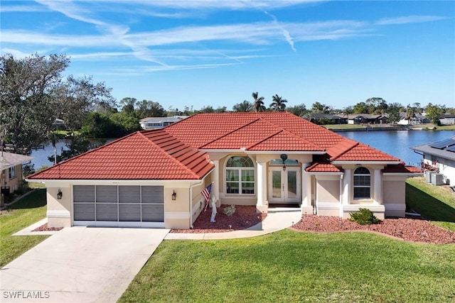 mediterranean / spanish home featuring a front lawn, a water view, and a garage