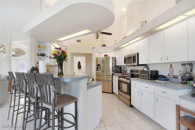 kitchen with light tile patterned floors, stainless steel appliances, white cabinetry, and a kitchen breakfast bar