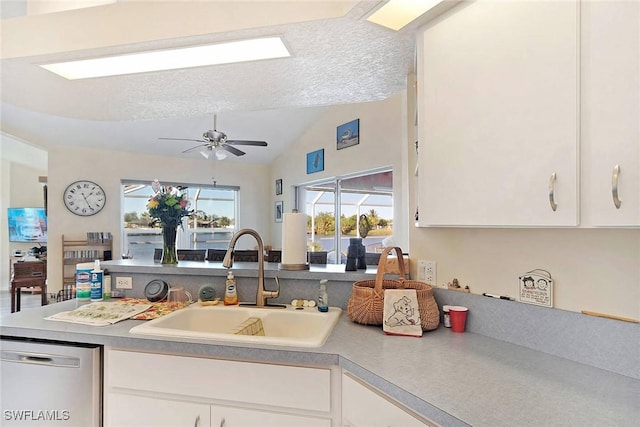 kitchen featuring dishwasher, vaulted ceiling, white cabinetry, and sink