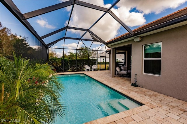 view of pool with glass enclosure and a patio area