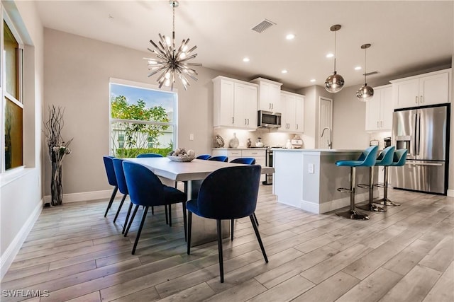 dining room featuring light hardwood / wood-style floors, sink, and an inviting chandelier