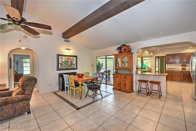 tiled dining space with lofted ceiling with beams, ceiling fan, and a healthy amount of sunlight