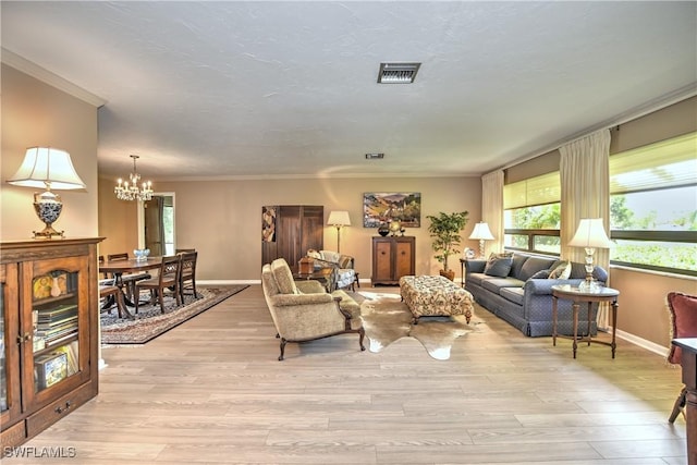 living room with light hardwood / wood-style flooring, ornamental molding, and a notable chandelier