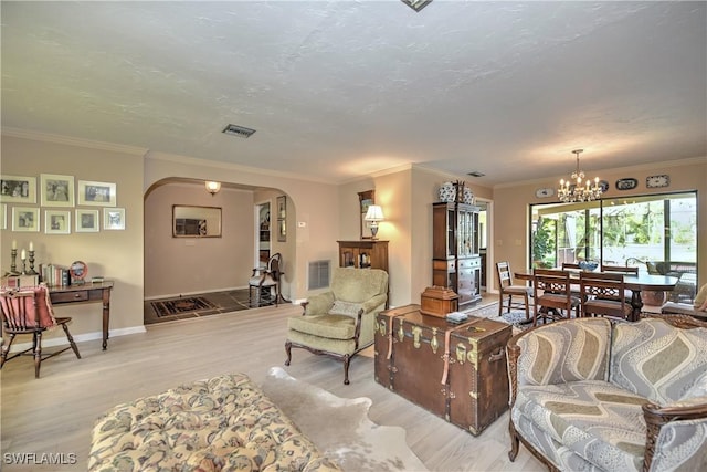 living room featuring a notable chandelier, crown molding, and light hardwood / wood-style flooring