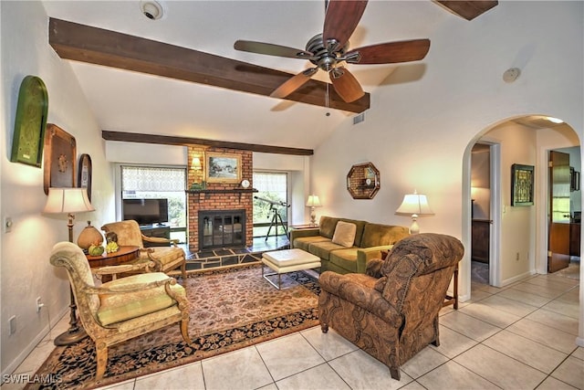 tiled living room with lofted ceiling with beams, ceiling fan, and a brick fireplace