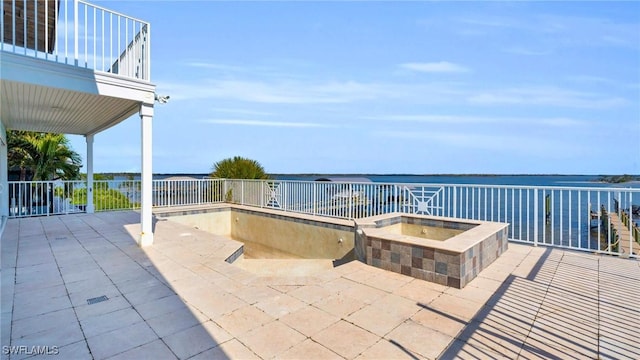 view of patio with an in ground hot tub and a water view