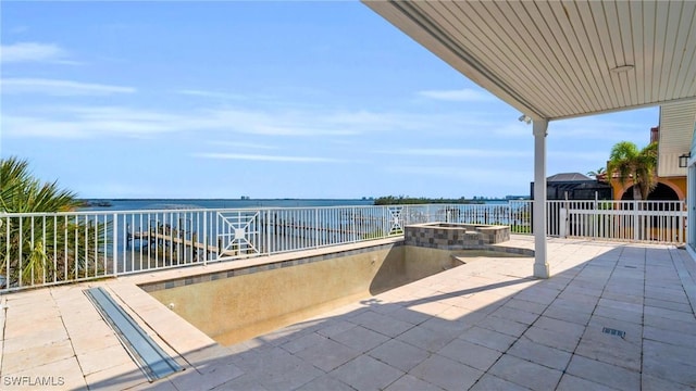 view of patio / terrace featuring a water view, a pool with connected hot tub, and fence