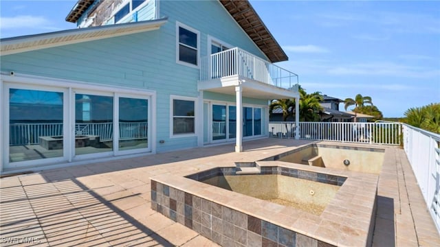 exterior space with an in ground hot tub, a patio area, and a balcony