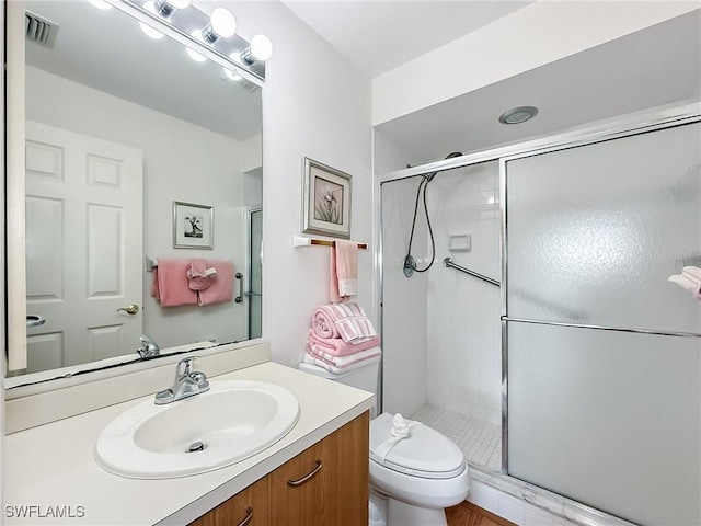 bathroom with vanity, toilet, and a shower with door