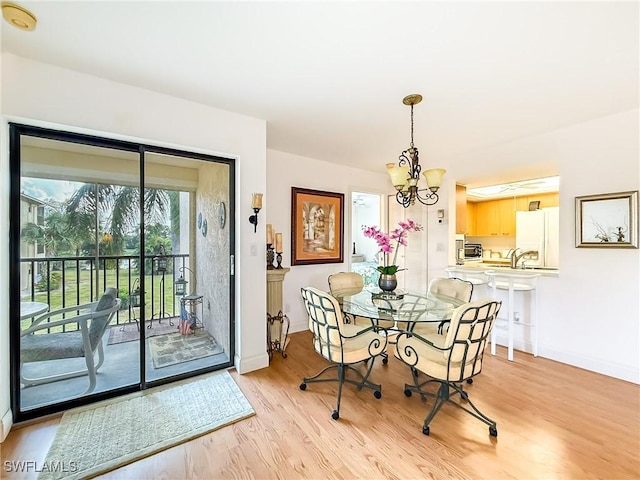 dining room with light hardwood / wood-style floors, a notable chandelier, and sink