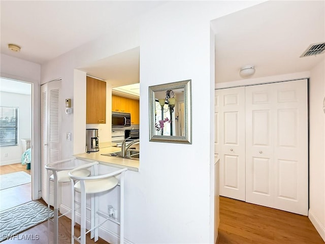 13276 White Marsh Ln Unit 3524, Fort Myers, FL 33912 - kitchen with wood finished floors, a kitchen bar, light countertops, and white range with electric stovetop