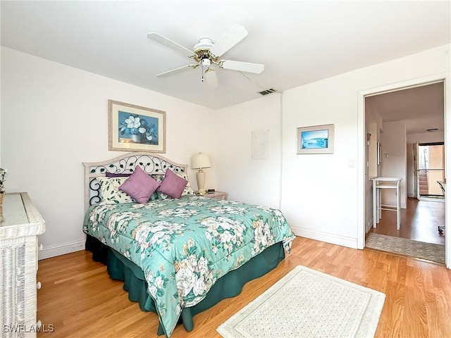 bedroom with ceiling fan, white fridge, and wood-type flooring