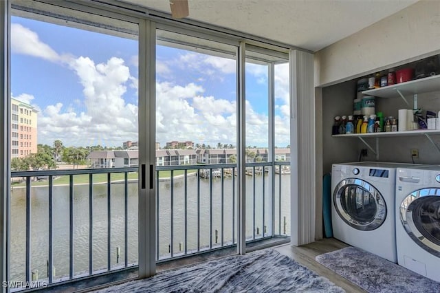 washroom with washer and dryer, a water view, and wood-type flooring