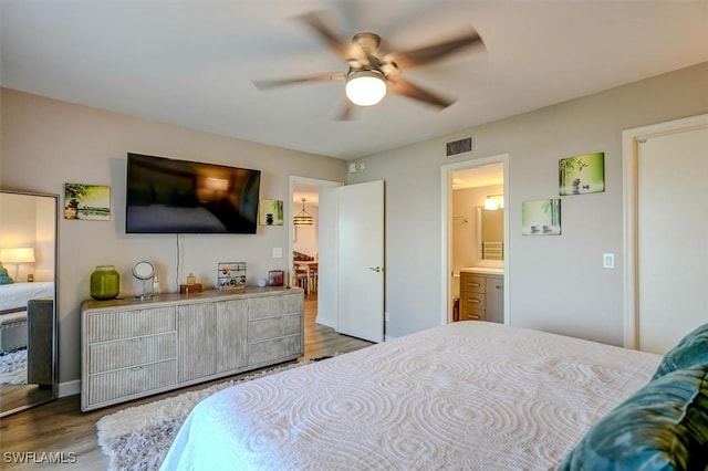 bedroom with ceiling fan, connected bathroom, and light hardwood / wood-style flooring