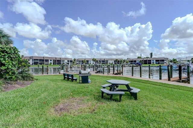 surrounding community with a water view, a yard, and a dock