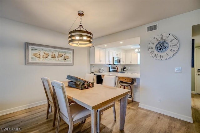 dining space with light wood-type flooring and a chandelier