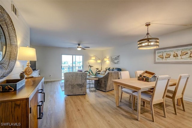 dining room with light hardwood / wood-style flooring and ceiling fan with notable chandelier