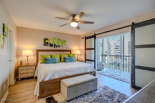 bedroom with ceiling fan, a barn door, access to exterior, and light hardwood / wood-style flooring